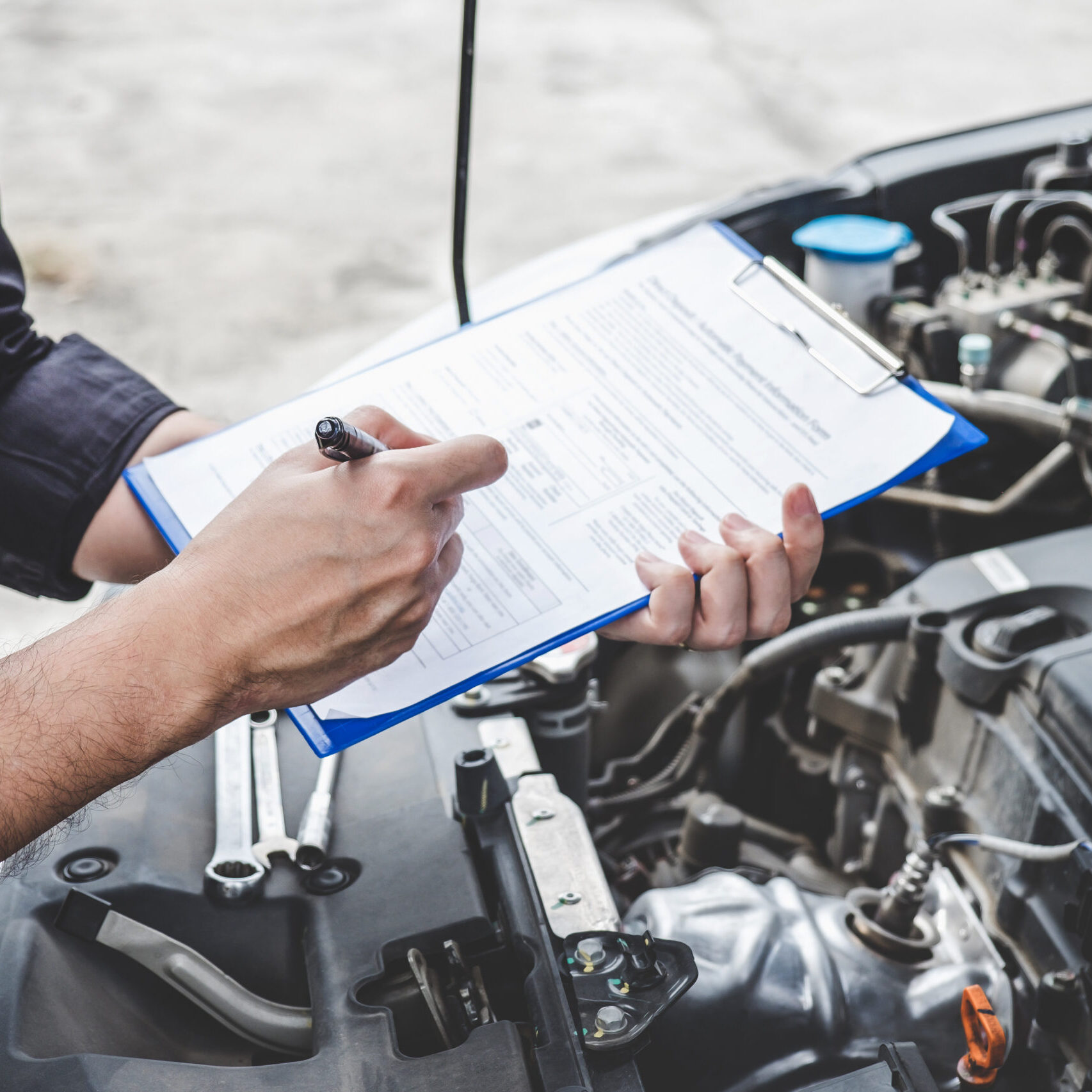 Services car engine machine concept, Automobile mechanic repairman checking a car engine with inspecting writing to the clipboard the checklist for repair machine, car service and maintenance.